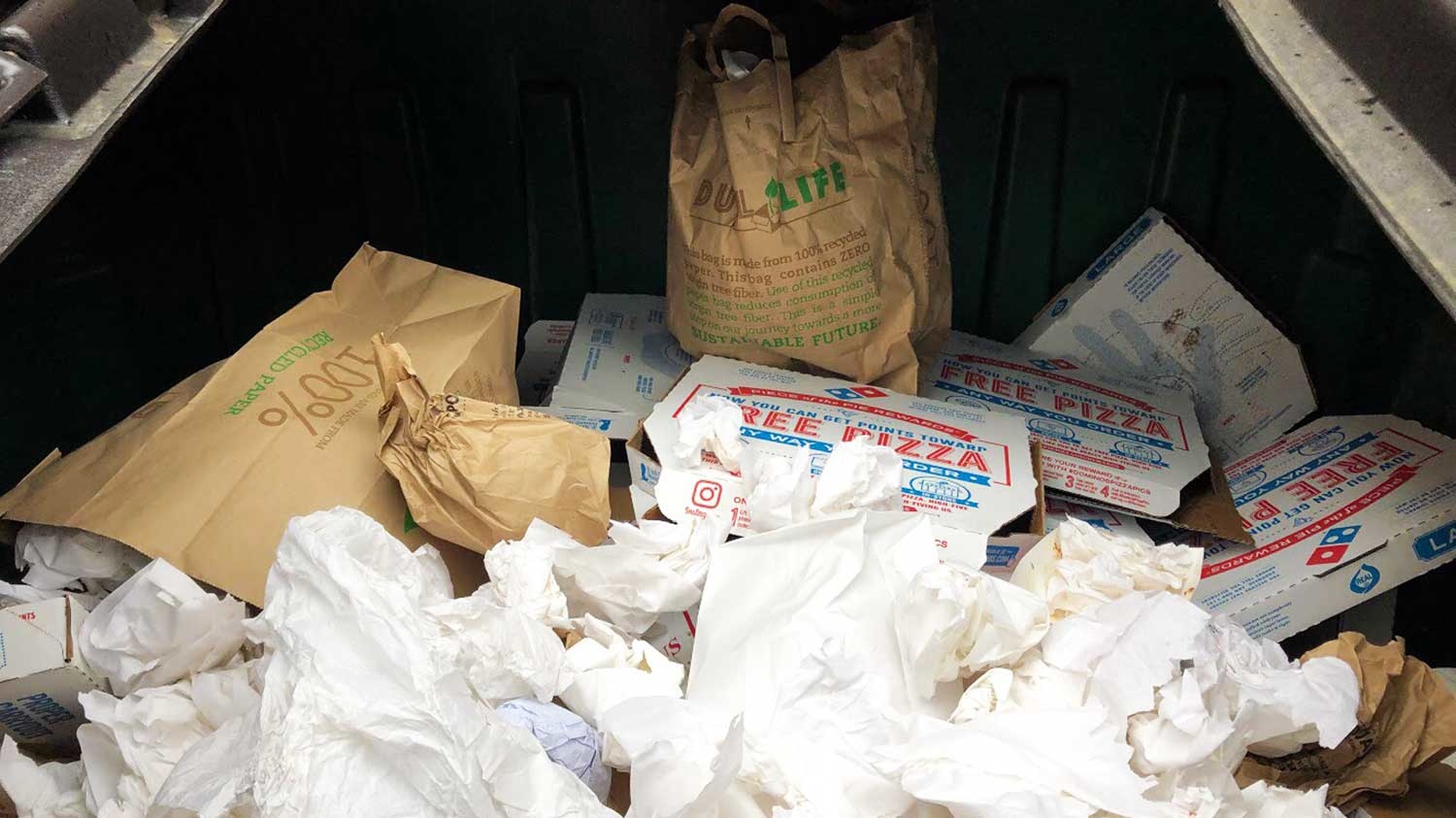 inside look at dumpster filled with paper towels and pizza boxes collected for composting