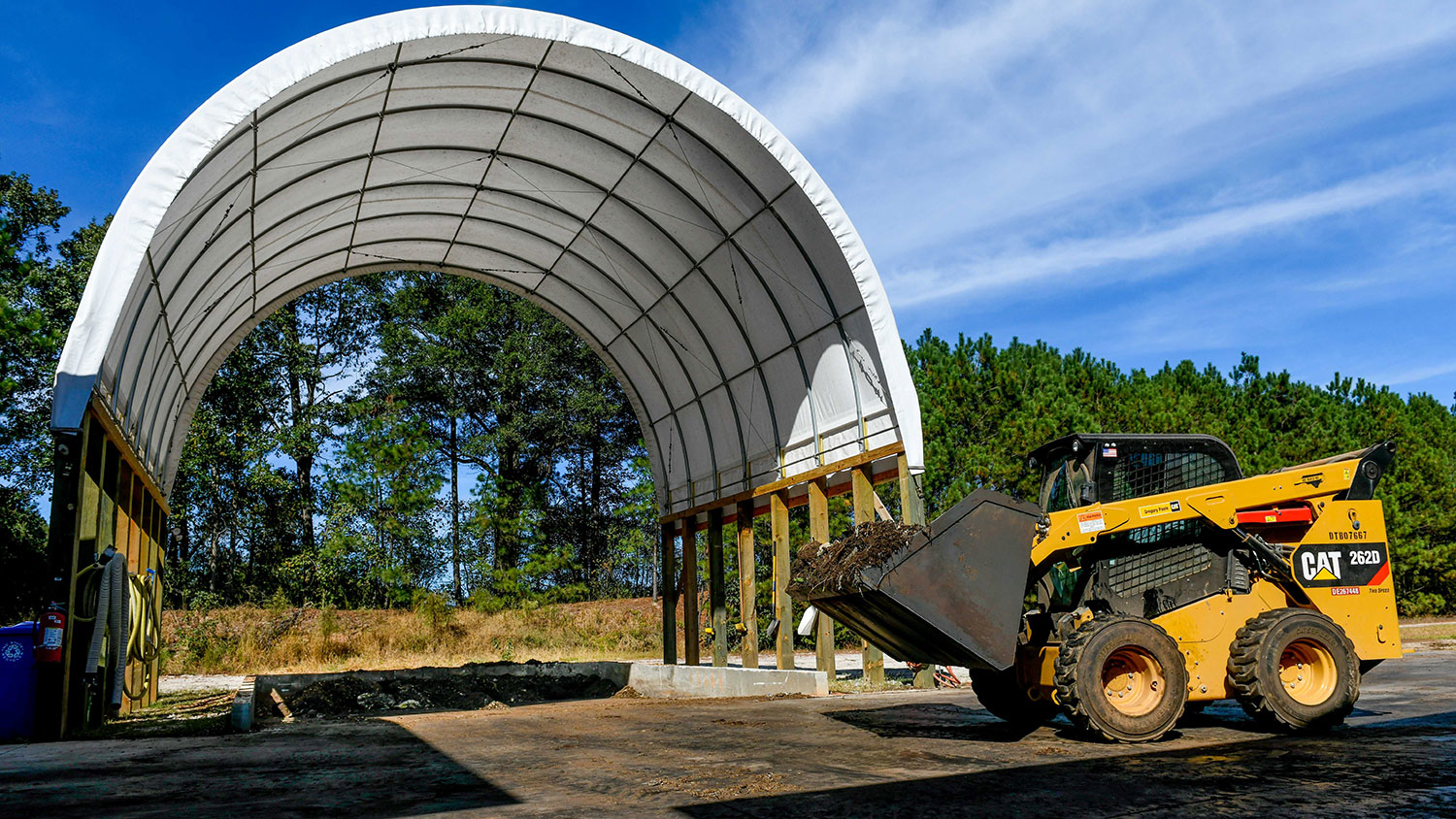 tractor with compost in front of hoop structure