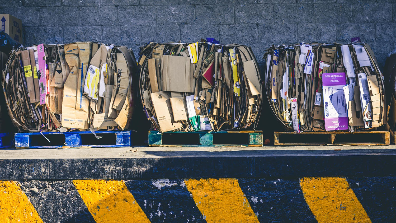 three pallets of bundled cardboard waste sit on a loading dock